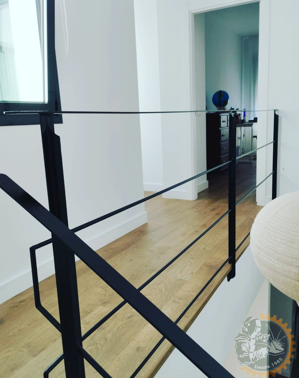Baranda negra con líneas horizontales junto al hueco de una escalera interior