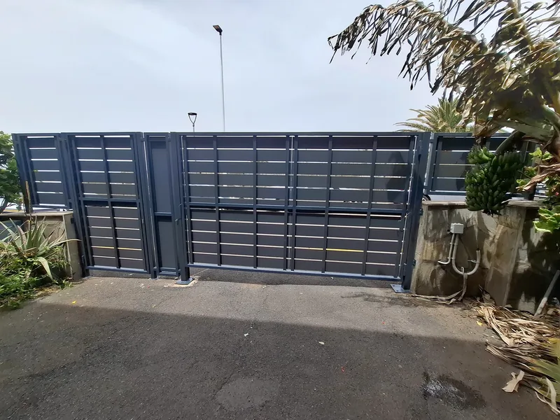 Cara interior del conjunto de accesos grises con sus perfiles verticales y lamas horizontales