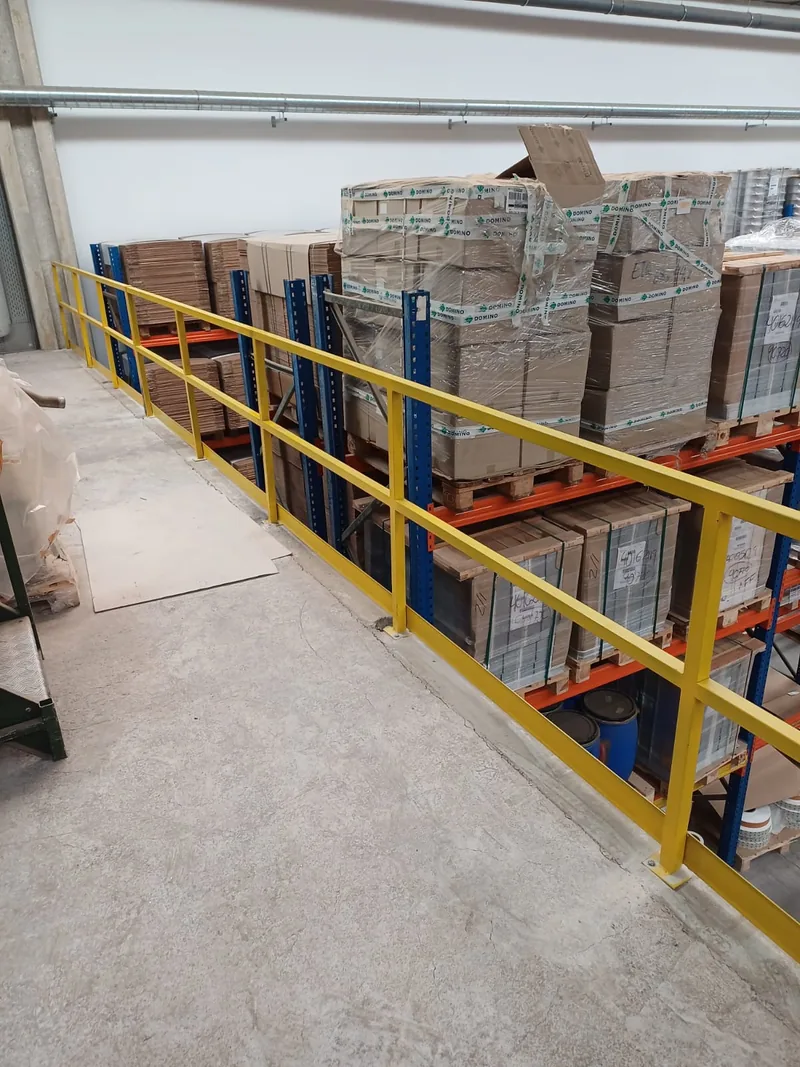 Barandilla amarilla de perfiles rectos junto al borde de un nivel elevado de un almacén