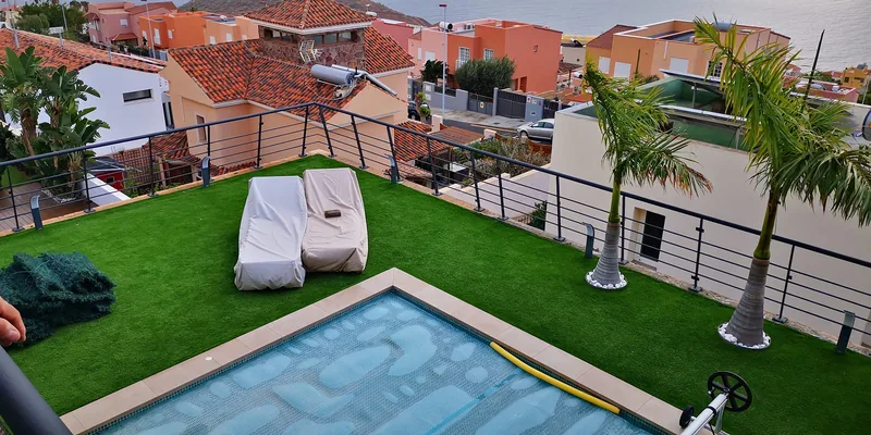 Barandilla oscura de líneas horizontales alrededor de una terraza con césped y piscina