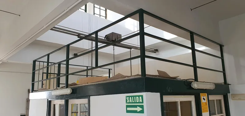 Barandilla oscura de travesaños horizontales alrededor de una zona elevada dentro de un edificio