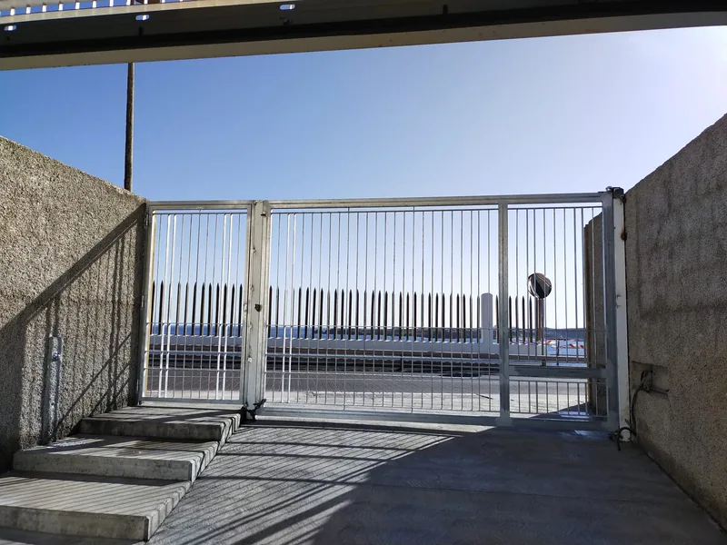 Cara interior de una cancela de barrotes verticales delante de una rampa y unos escalones