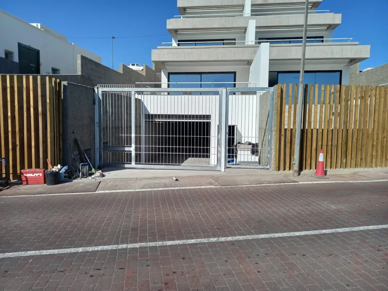 Cancela de barrotes vista desde la calle delante de un edificio con acceso a garaje