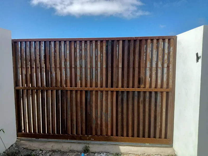 Cara opuesta de la cancela de lamas verticales con marco y travesaño horizontal central