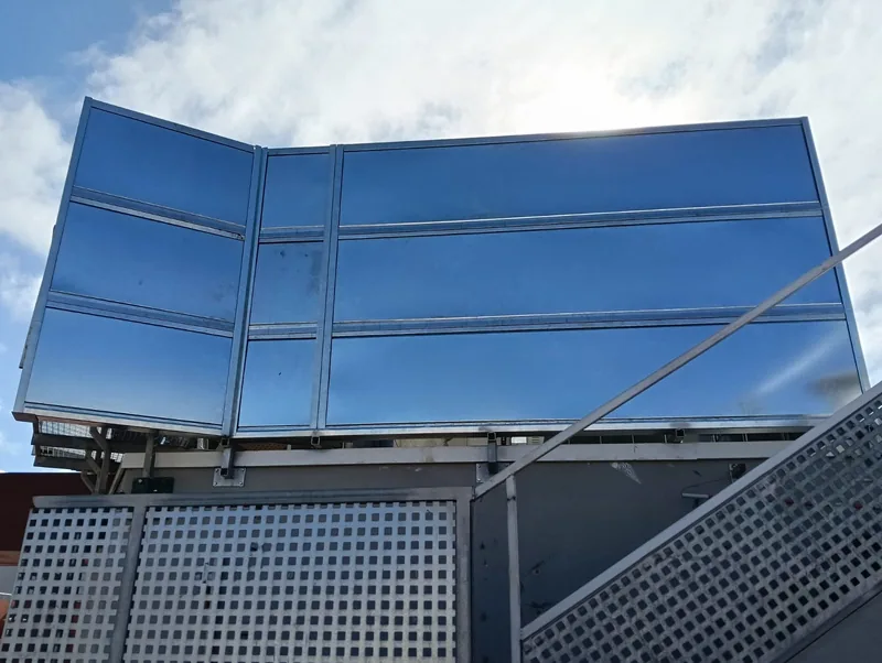 Frente de paneles metálicos opacos visto desde una escalera de acceso a una azotea