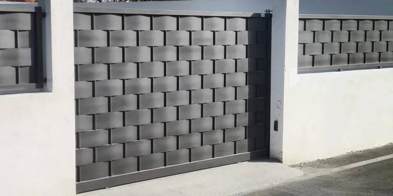 Puerta metálica gris con bandas entrelazadas y paneles laterales a juego