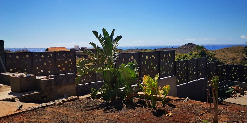 Vista amplia de los paneles perforados junto al jardín y a la vegetación exterior