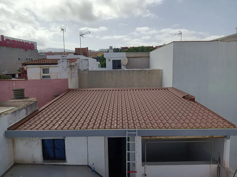 Cubierta rojiza de acabado de teja entre paredes, con un perfil gris en el borde frontal