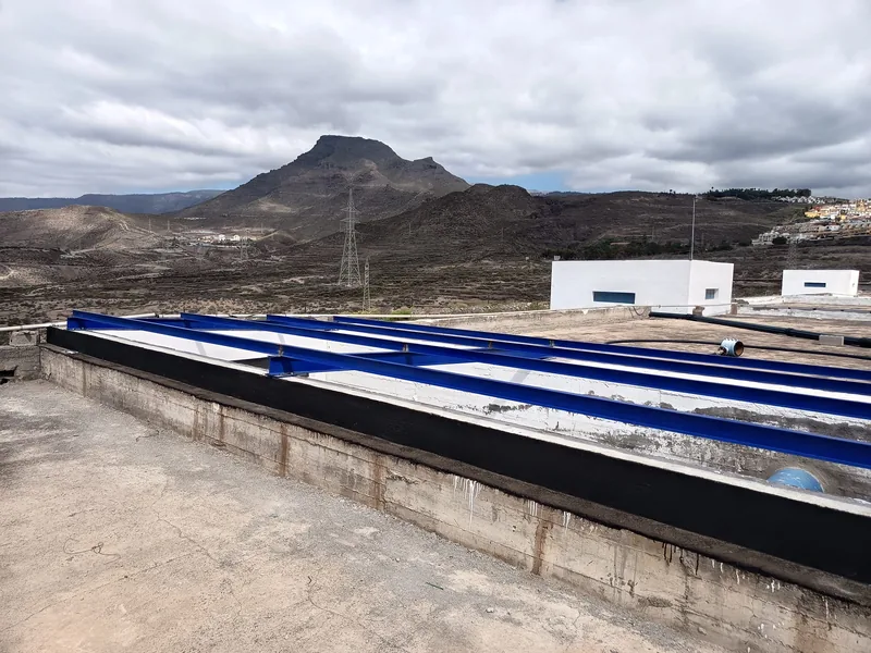 Perfiles metálicos azules dispuestos sobre un hueco alargado antes de colocar la cubierta