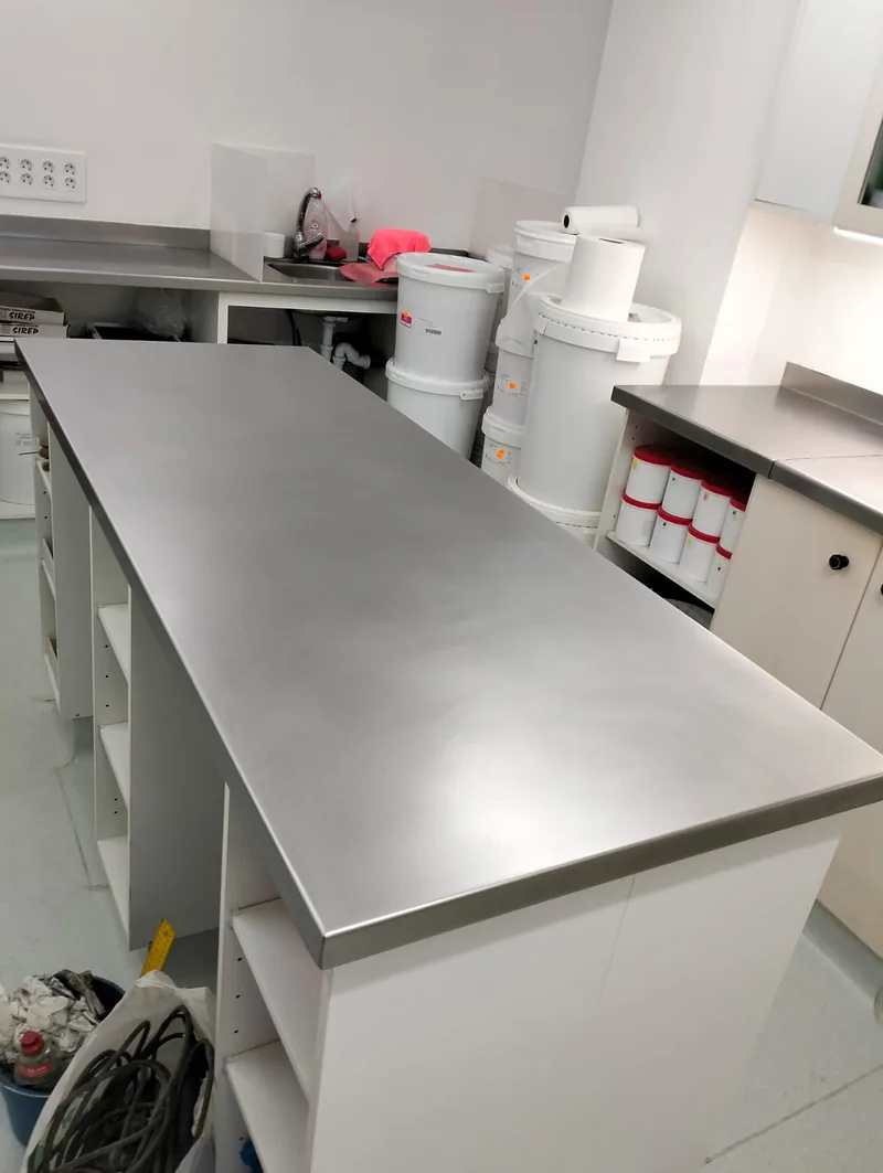 Encimera metálica rectangular sobre un mueble blanco y superficies metálicas junto a las paredes