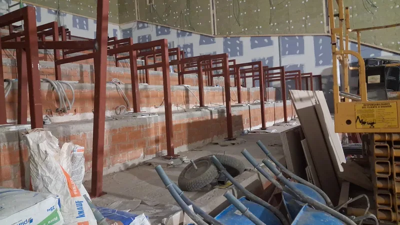 Bastidores metálicos rojizos de distintas alturas sobre los niveles escalonados de una sala en obras