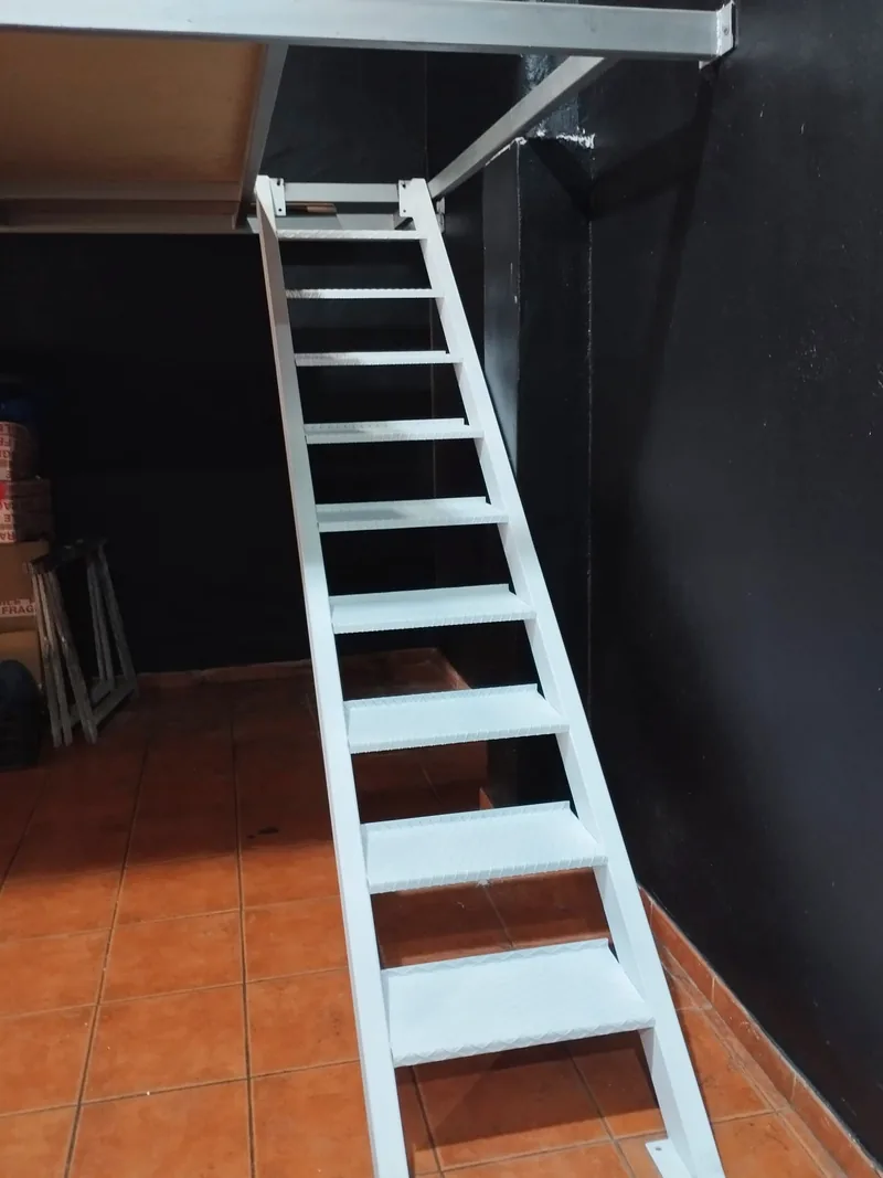 Escalera estrecha de largueros blancos y peldaños metálicos vista desde su parte inferior