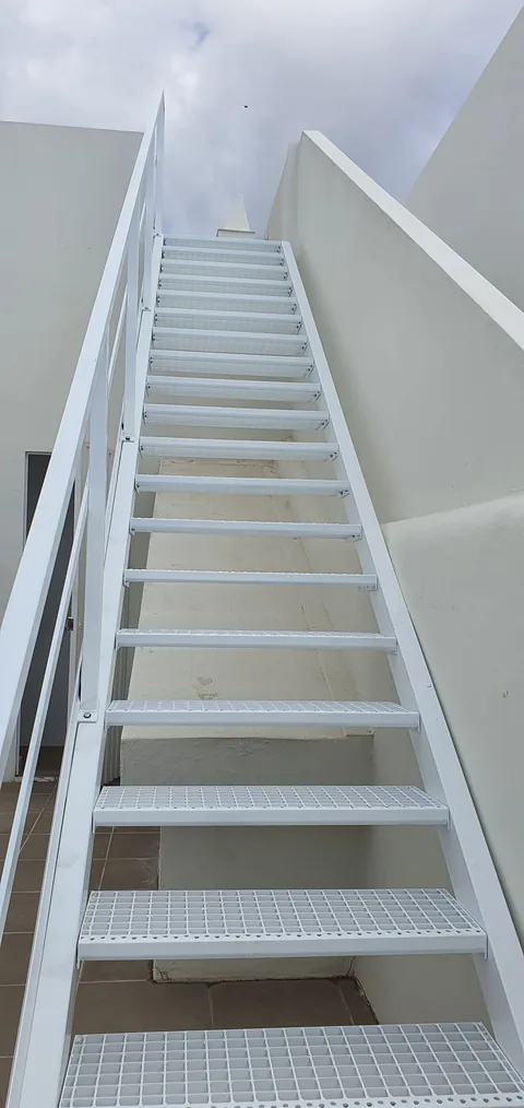 Peldaños blancos de rejilla de una escalera exterior vistos desde su base