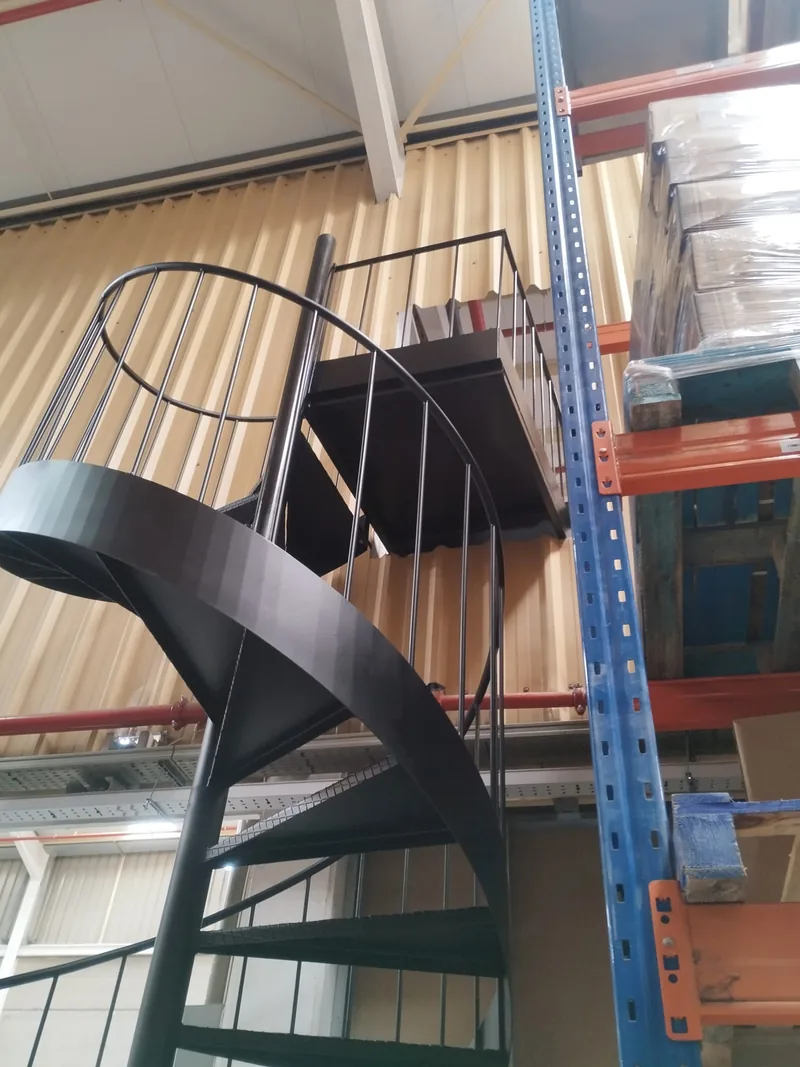 Detalle de los peldaños superiores, la barandilla y el desembarco de una escalera de caracol negra