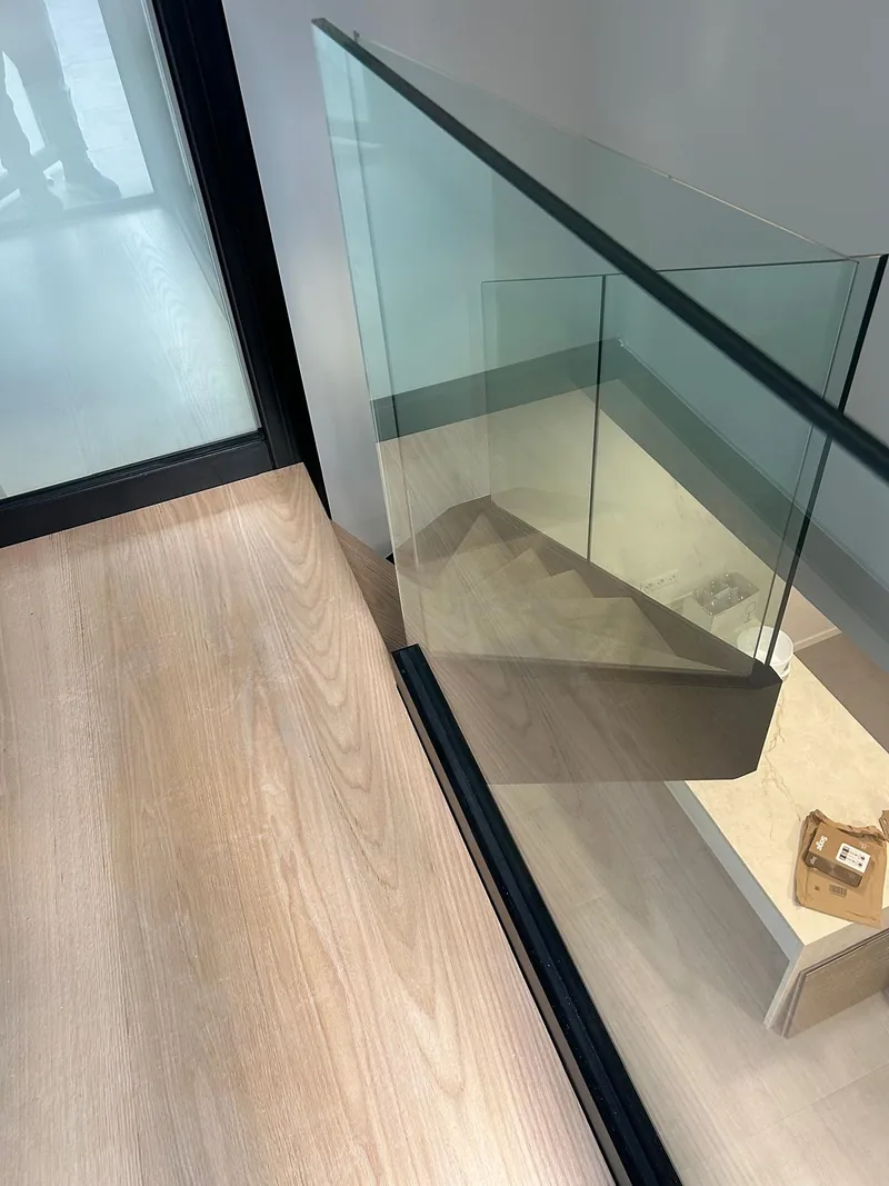 Paneles transparentes y perfil oscuro junto al desembarco superior de una escalera interior