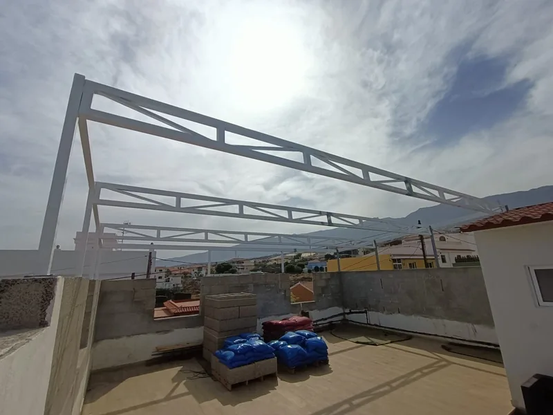 Pilares y cerchas metálicas blancas antes de colocar los paneles de una cubierta