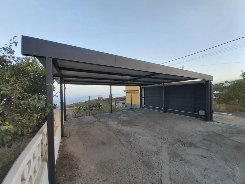 Estructura metálica gris con cubierta clara y puerta ancha al fondo de un espacio exterior