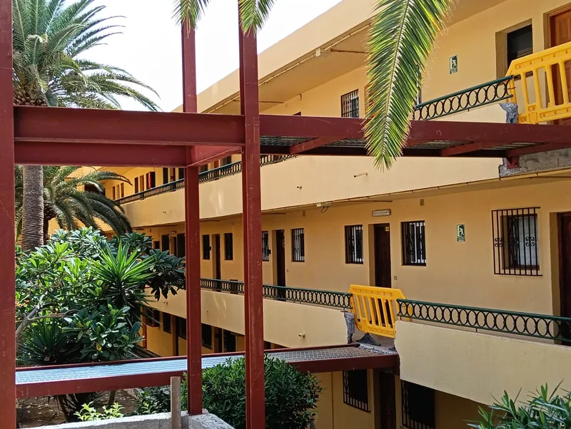 Tramos de vigas rojizas con chapa nervada que enlazan una estructura exterior con corredores de un edificio