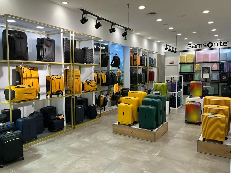 Expositores de bastidor metálico dorado con baldas claras en el interior de una tienda de equipaje