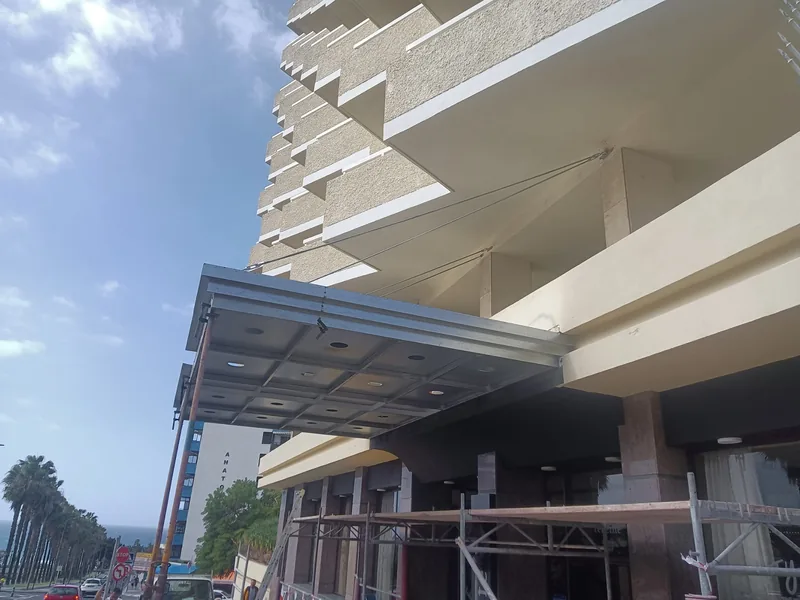 Cara inferior de una marquesina metálica durante su montaje sobre la entrada de un edificio