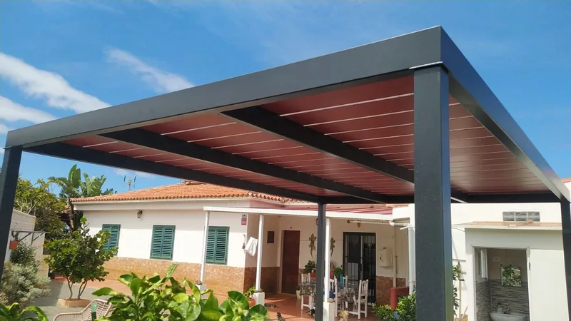 Detalle de las vigas oscuras y la cubierta de la pérgola frente a la vivienda