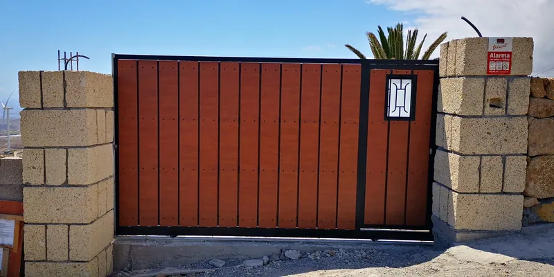 Cara opuesta del portón marrón instalado entre dos pilares de bloque
