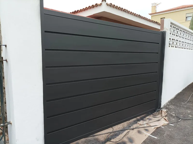 Puerta gris oscura de paneles horizontales instalada entre muros blancos