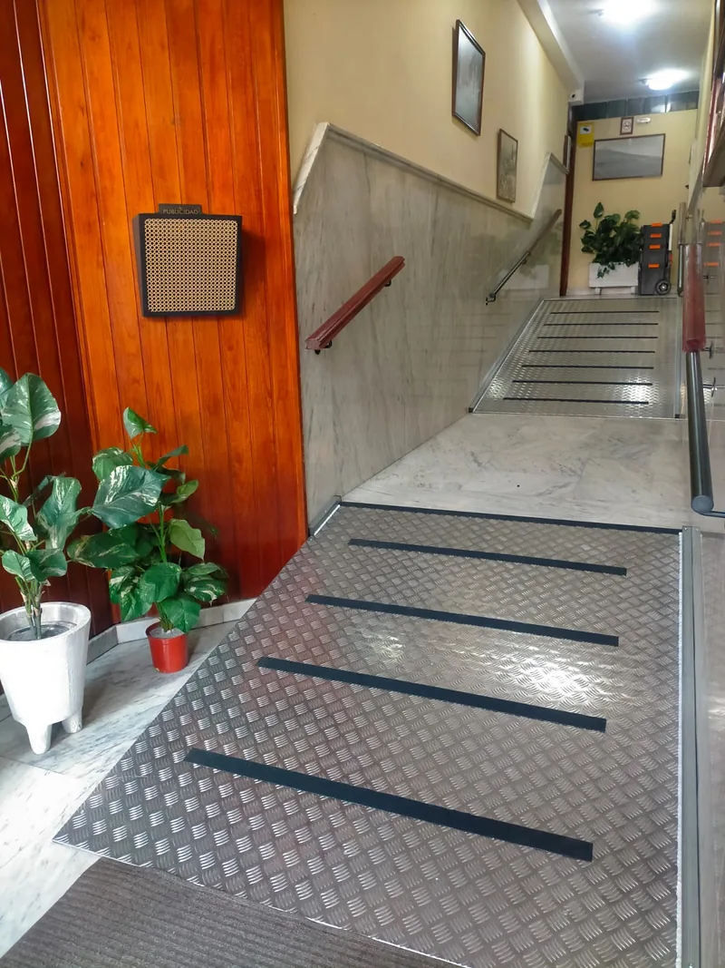 Rampa metálica de superficie en relieve con bandas oscuras en un portal interior