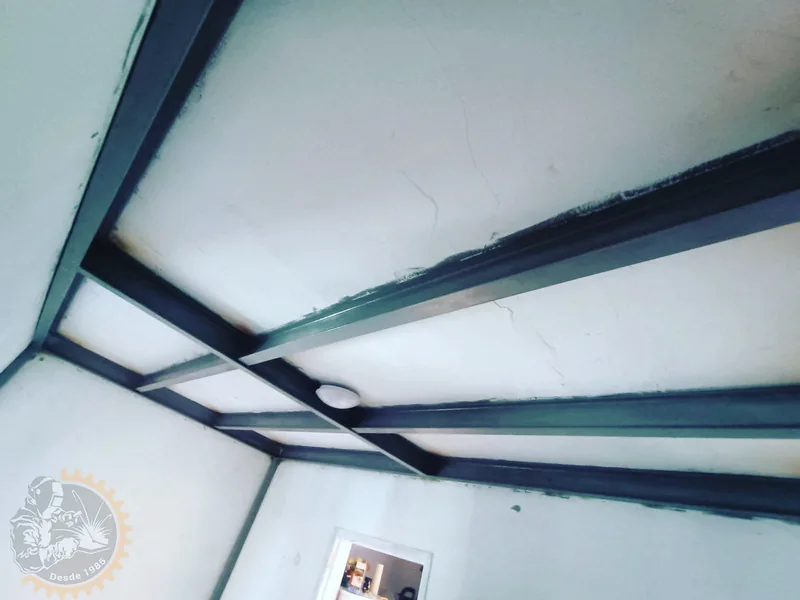 Vigas metálicas oscuras instaladas bajo el techo de una habitación