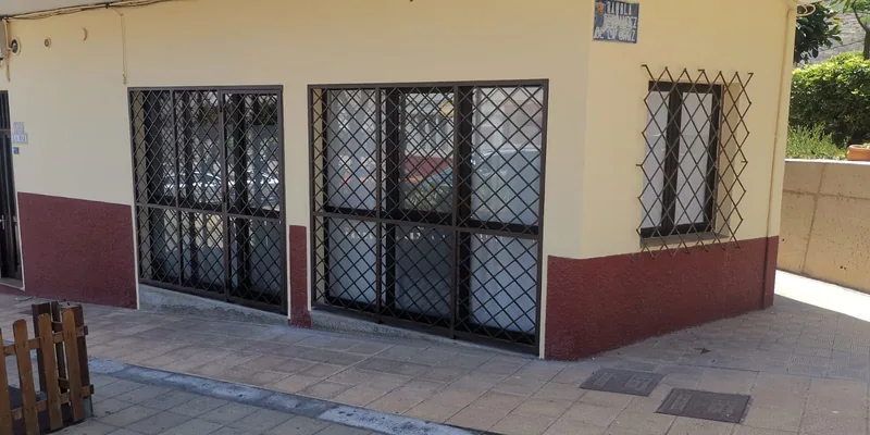 Rejas negras con dibujo en rombos en puertas y ventana de una fachada amarilla