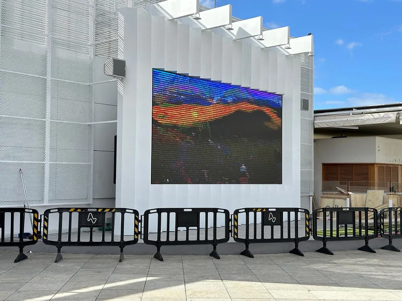 Revestimiento blanco de piezas metálicas plegadas y paneles perforados alrededor de una pantalla exterior