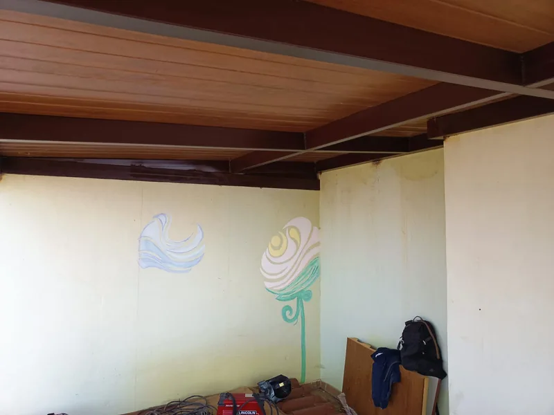 Vigas metálicas oscuras cruzadas bajo paneles de techo de tono madera en una habitación